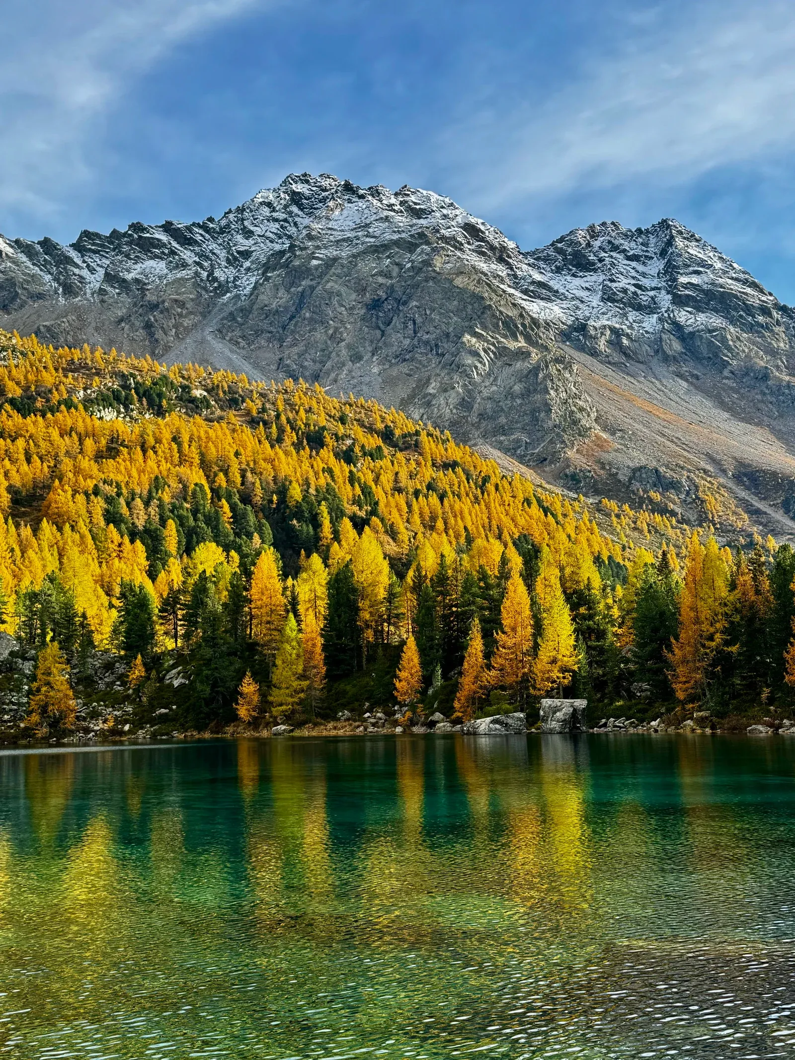 Montagnes et mélèzes dorés se reflétant dans un lac alpin